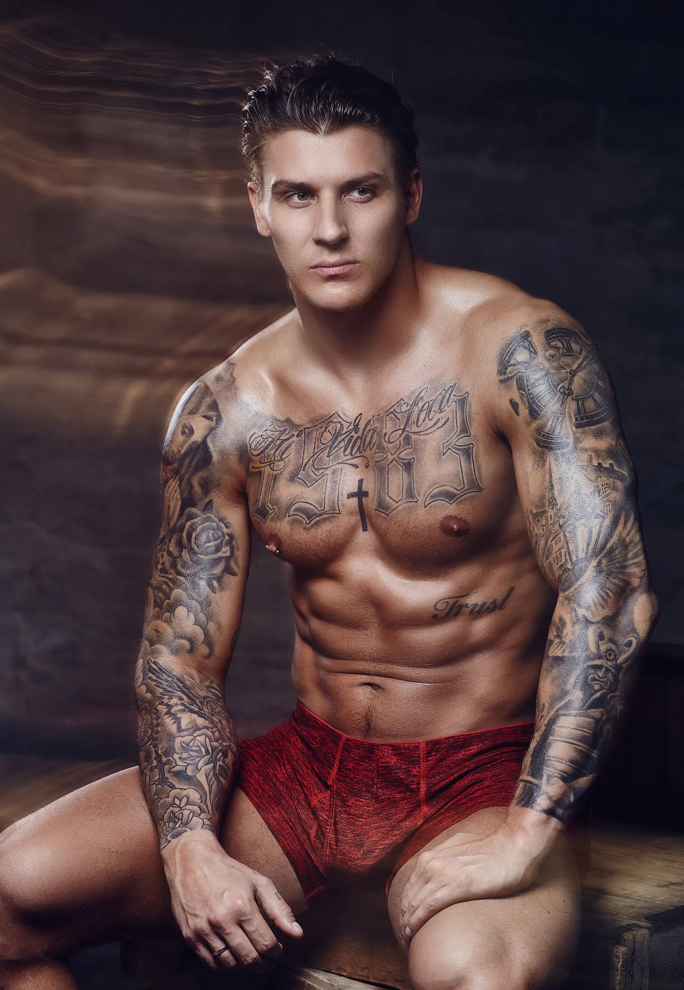 Homme athlétique torse nu, couvert de tatouages, pensif